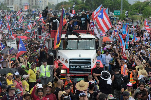 Puerto Rican singer Ricky Martin, front atop truck, participates with other local celebrities in a protest demanding the resignation of governor Ricardo Rossello in San Juan, Puerto Rico on Monday